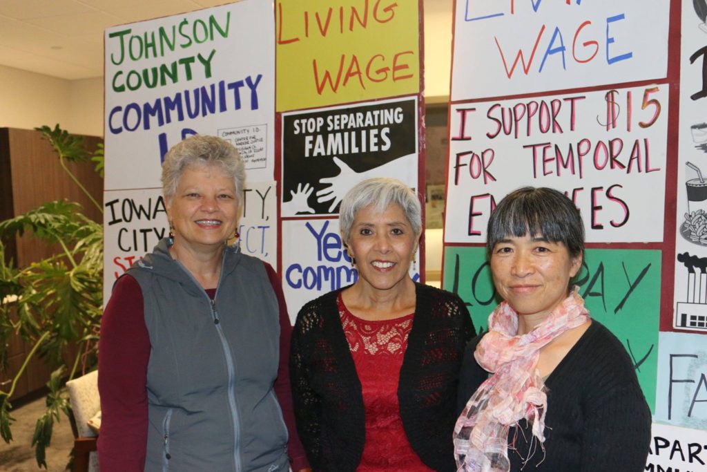 Three women standing in front of a wall with signs.