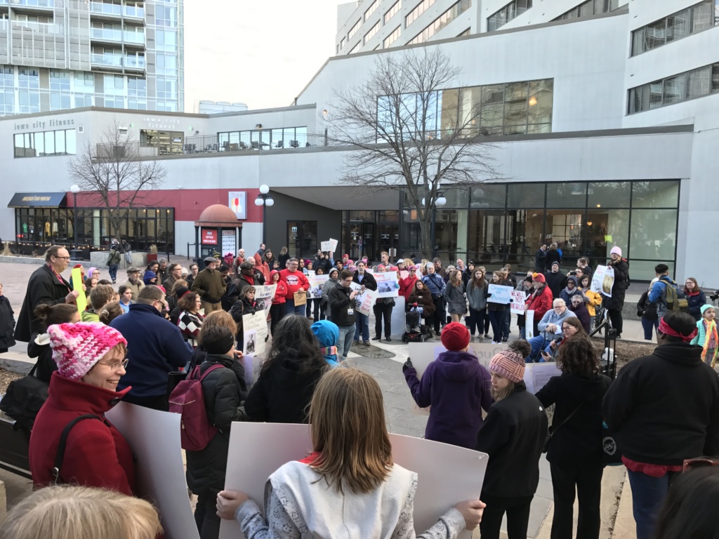 A crowd of people standing on the sidewalk.