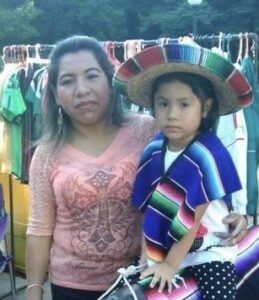 A woman and child in mexican clothing at an outdoor market.